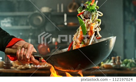 Freeze Motion of Wok Pan with Flying Asian Meal in the Air. Freeze Motion of Wok Pan with Flying Asian Meal in the Air. 112197024