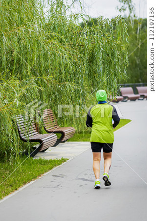 Rear view of man jogging in park, summer day, health care concept, weight loss Rear view of man jogging in park, summer day, health care concept, weight loss 112197136
