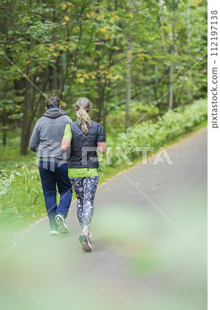 Back view of young woman and man running in forest park. Fitness, sport and jogging 112197138