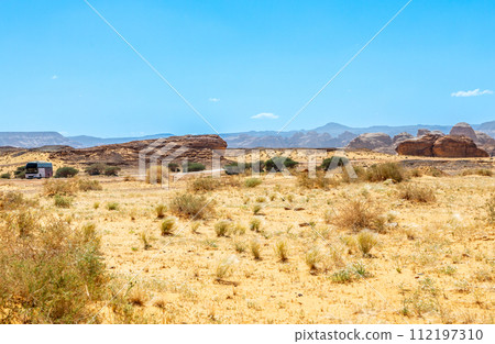 Desert sand landscape with mountains in the background and road with bus, near Al Ula, Saudi Arabia 112197310