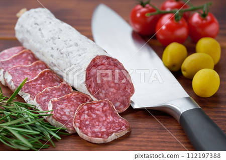 Fuet sausage with spices and herbs on a cutting board close up. 112197388