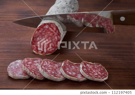 Spanish Salami sausage cut in slices on a wooden table. Traditional Spanish sausage. 112197405