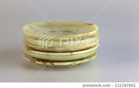 Empty saucers made of multi-colored onyx in yellow-orange tones on a white background. 112197601