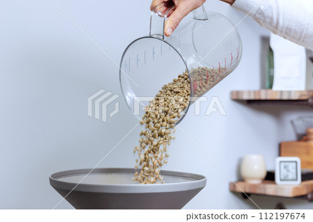 Pouring raw coffee beans into oven for roasting 112197674