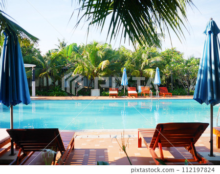 Hotel pool surrounded by palm trees 112197824