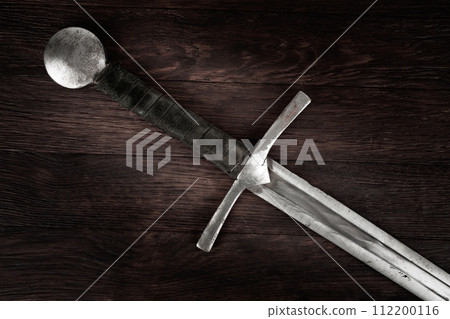 Medieval sword on wooden background. Medieval sword on wooden background. 112200116