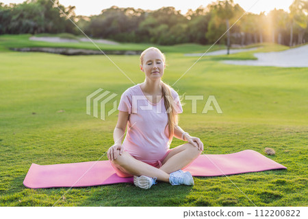 Energetic pregnant woman takes her workout outdoors, using an exercise mat for a refreshing and health-conscious outdoor exercise session 112200822