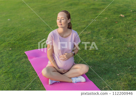 Energetic pregnant woman takes her workout outdoors, using an exercise mat for a refreshing and health-conscious outdoor exercise session Energetic pregnant woman takes her workout outdoors, using an exercise mat for a refreshing and health-conscious outdoor exercise session 112200946