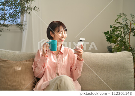 A woman looking at her smartphone in the living room 112201148