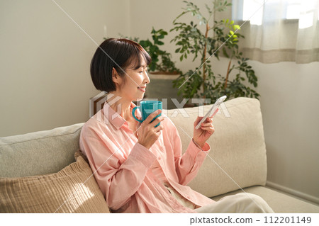 A woman looking at her smartphone in the living room 112201149