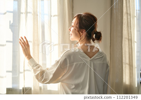 Woman standing by the window 112201349