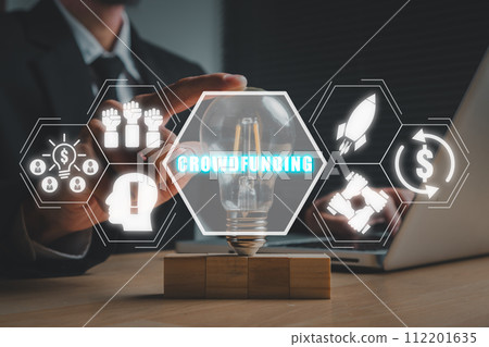 Crowdfunding concept, Businessman hand touching lightbulb on office desk with crowdfunding icon on virtual screen. 112201635