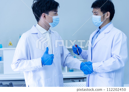 Close up Two asian scientist men team partner shake hands together. Crop Men researcher holding chemistry science tube experiment biotech sample in laboratory. Close up hand corporate partnership 112202450