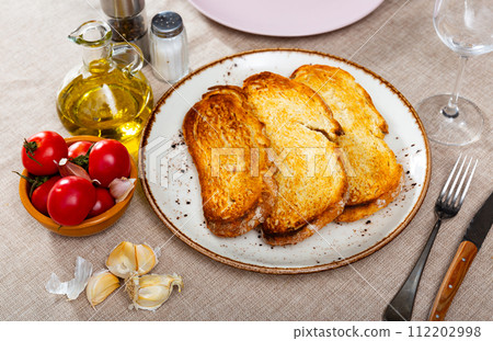 Preparation of Catalan tapas Pan con tomate - grilled bread topped with mixture of grated tomatoes and garlic. Ingredients ready for cooking served on table 112202998