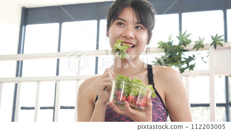 Healthy woman workout holding organic salad bowl healthy lifestyle. Wellness Asian women dressing organic green salad tomato vegetable dish. Beautiful girl healthcare vegan wellness lifestyle concept Healthy woman workout holding organic salad bowl healthy lifestyle. Wellness Asian women dressing organic green salad tomato vegetable dish. Beautiful girl healthcare vegan wellness lifestyle concept 112203005