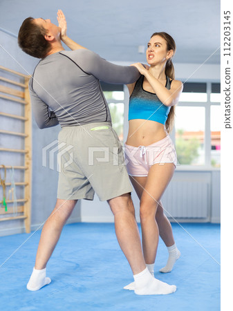 Young girl practicing self-defense techniques in pair with middle-aged man 112203145