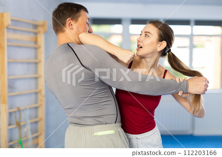 Young girl practicing self-defense techniques in pair with middle-aged man 112203166