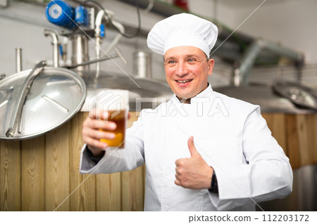 Portrait of positive man brewmaster with glass of beer Portrait of positive man brewmaster with glass of beer 112203172