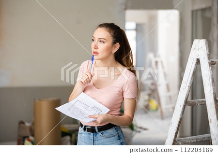 Woman checking plan of house being renovated Woman checking plan of house being renovated 112203189