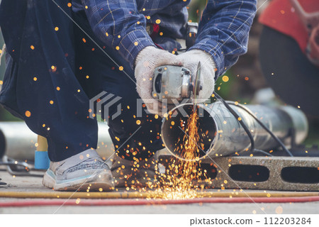 Locksmith use Welding machine cut metal process. Construction Worker hands using Welding machinery iron metal sparking. Men hands wear protective glove Hot flame metal work cutting fire iron workshop 112203284