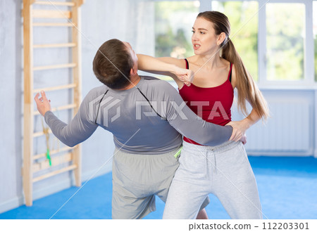 Self-defense training - woman practicing blows to the head of male attacker Self-defense training - woman practicing blows to the head of male attacker 112203301