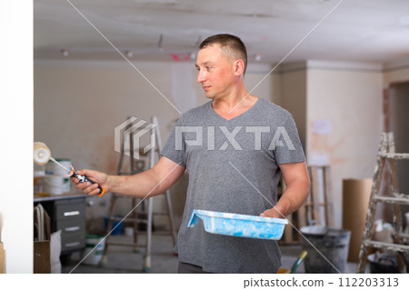 Man painting wall in apartment Man painting wall in apartment 112203313