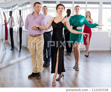 Multinational group lesson - waltz training, male and female participants stand in pairs Multinational group lesson - waltz training, male and female participants stand in pairs 112203336