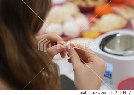The process of making a massage candle using ingredients oils and wax measure weigh stir add close-up of women's hands. food thermometer measure wax temperature women's party women witches witchcraft 112203467
