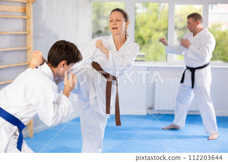 Woman and man in kimono sparring together in sport gym during karate training 112203644