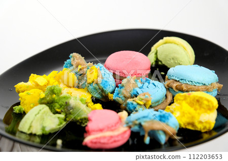 Broken macaroons on a black plate. 112203653