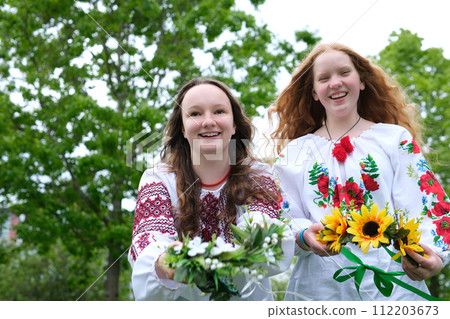 two beautiful young girls wearing embroidered shirts sunflowers Field flowers red bright sunny hair against background place for text Ivan Kupala celebrating the festivities of the Ukrainian people two beautiful young girls wearing embroidered shirts sunflowers Field flowers red bright sunny hair against background place for text Ivan Kupala celebrating the festivities of the Ukrainian people 112203673