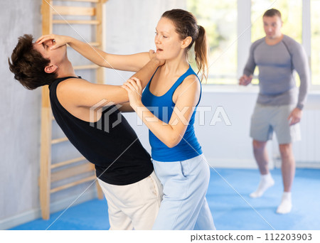 Guy paired up with woman to perform effective impact on pain points while learning self-defense. Guy paired up with woman to perform effective impact on pain points while learning self-defense. 112203903