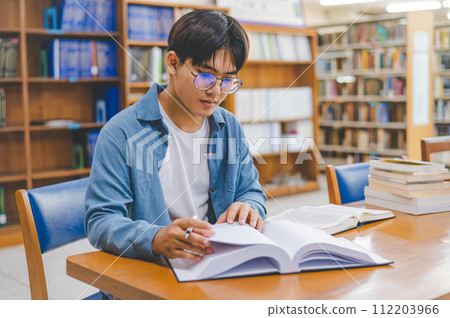 Male college students are working on laptops and searching for books to study, make reports, find useful information in college room. Concept of reading, learning and intelligence. 112203966