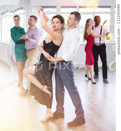 Man and woman in elegant clothes performing ballroom dance in dancing room during celebration or party Man and woman in elegant clothes performing ballroom dance in dancing room during celebration or party 112203994