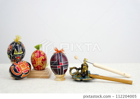 special devices for coloring eggs four eggs of different colors red yellow black with tufts of thread on a white background space for text postcard easter eggs holiday celebration of easter 112204005
