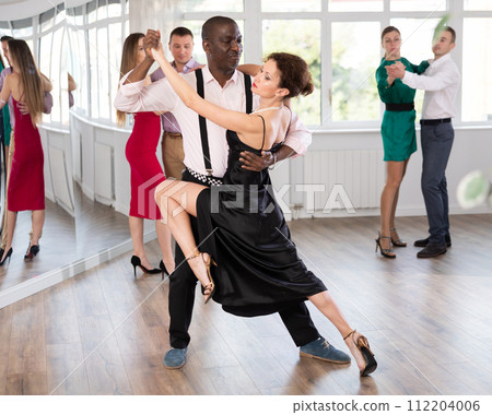 Woman dances incendiary tango with African man partner during choreography lesson Woman dances incendiary tango with African man partner during choreography lesson 112204006