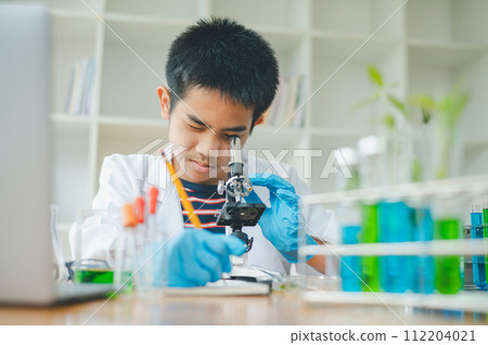 Asian male science students looking through a microscope and tests of plants in the classroom. Learning about scientific experiments on plant species. 112204021