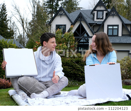 teenagers boy and girl sitting on a picnic with white boxes empty space for advertising text pizza cake on a plaid sportswear thumb up look at each other love for food joy approval tasty picnic 112204123