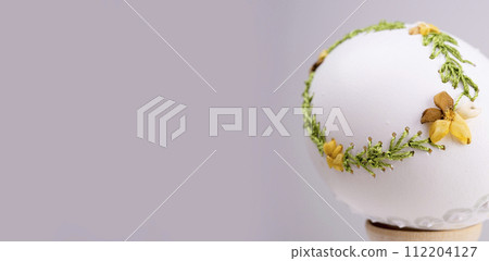 Easter holiday egg on a banner embroidery with ribbons on a real white egg is handmade instead For text advertising invitation ornament to paint eggs beautiful postcard congratulation 112204127