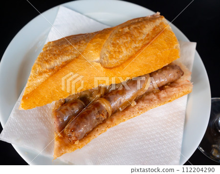Hearty snack is crispy baguette stuffed with juicy fatty sausages and passioned onions. 112204290
