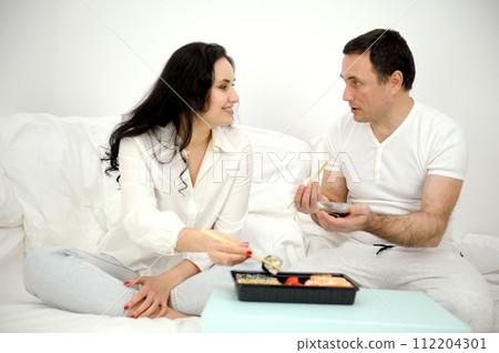 sushi in bed Beautiful Ethnic Couple Sitting on the Bed Eating Breakfast Together and Looking At Each Other In Love. Celebrating Valentines Day Together By Going To a Fancy Hotel Suite. sushi in bed Beautiful Ethnic Couple Sitting on the Bed Eating Breakfast Together and Looking At Each Other In Love. Celebrating Valentines Day Together By Going To a Fancy Hotel Suite. 112204301