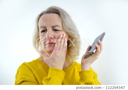 toothache woman sadly holds her hand on her cheek white manicure orange clothes studio telephone in hand call to the doctor headache 112204347