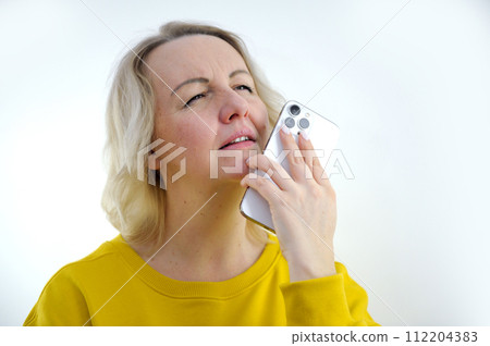 Cheerful attractive woman holding smartphone, enjoying chatting in social networks, pondering and thinking, using mobile app for dating on the phone, isolated on white, copy space 112204383
