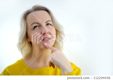 Young female blonde worried and bites her nails with expression of fear emotion on face. Stress from studying, working, relationships, illness isolated on white background Young female blonde worried and bites her nails with expression of fear emotion on face. Stress from studying, working, relationships, illness isolated on white background 112204436