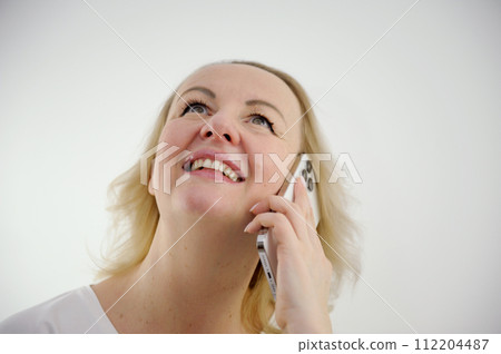 woman happy joyfully threw her head up talking on the phone with pleasure bliss pleasant emotions and beautiful teeth cute middle-aged woman in studio white background advertising like a sincere smile woman happy joyfully threw her head up talking on the phone with pleasure bliss pleasant emotions and beautiful teeth cute middle-aged woman in studio white background advertising like a sincere smile 112204487