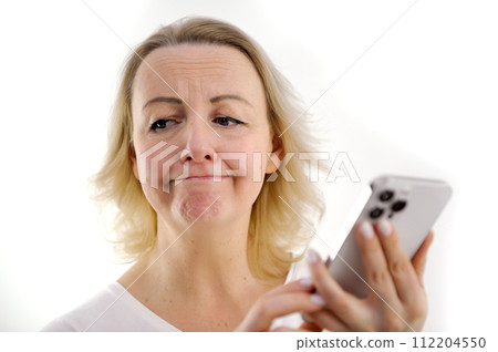 unhappy dissatisfied woman is dissatisfied with message upset sad little frowning sadness disappointment in hands of mobile phone white background surprise trouble with tet little reddened face 112204550