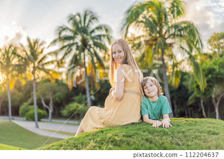 Heartwarming outdoor bonding as a pregnant mom and her son enjoy quality time together, savoring the beauty of nature and creating cherished moments 112204637