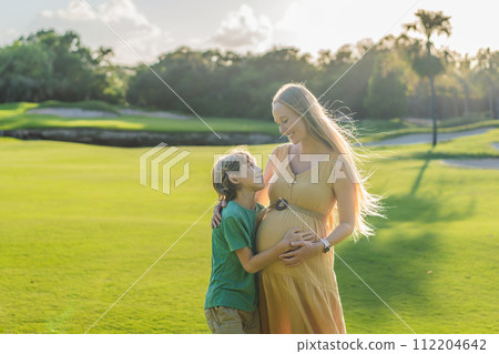 Heartwarming outdoor bonding as a pregnant mom and her son enjoy quality time together, savoring the beauty of nature and creating cherished moments 112204642