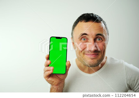 Positive millennial man showing huge brand new smartphone with empty screen and thumb up over white studio background, mockup, panorama with copy space, newest mobile app concept 112204654