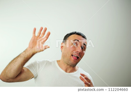 Win fun vacation travelDifferent cheerful positive emotions of an adult man with gray black hair Open funny cheerful blue eyes White t-shirt gray background wrinkle forehead stick out tongue 112204660